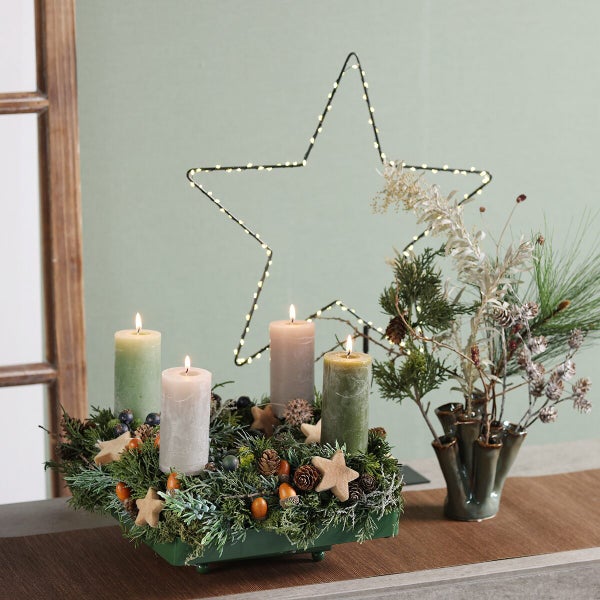 Weihnachtliche Tischdekoration mit Adventskranz aus Tannengrün, vier Kerzen und beleuchtetem LED-Stern als festliche Tischschmuck-Idee.