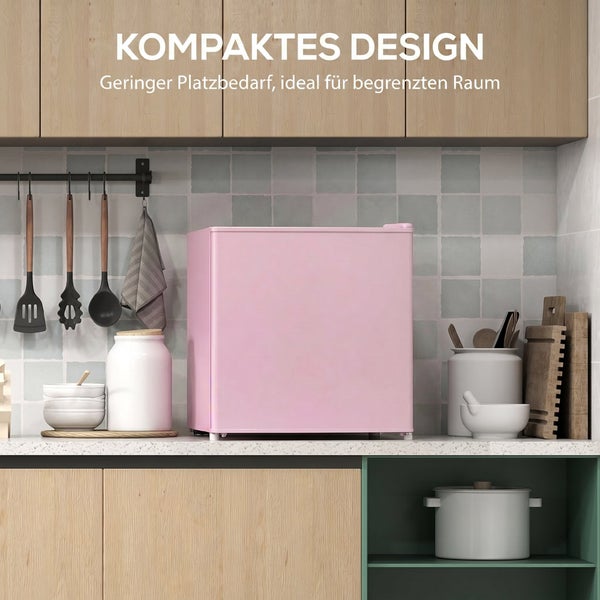 Kompakter rosa Kühlschrank auf einer Küchenarbeitsplatte, platzsparendes Design in einer modernen Küche mit Holzschränken und Utensilien.