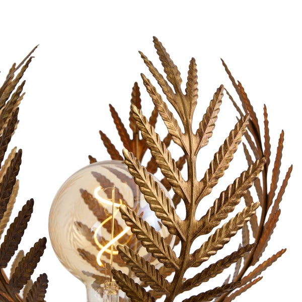 Detailaufnahme einer Leuchte mit goldfarbenen Metallblättern in Farnoptik und einem sichtbaren Leuchtmittel mit Glühfaden.