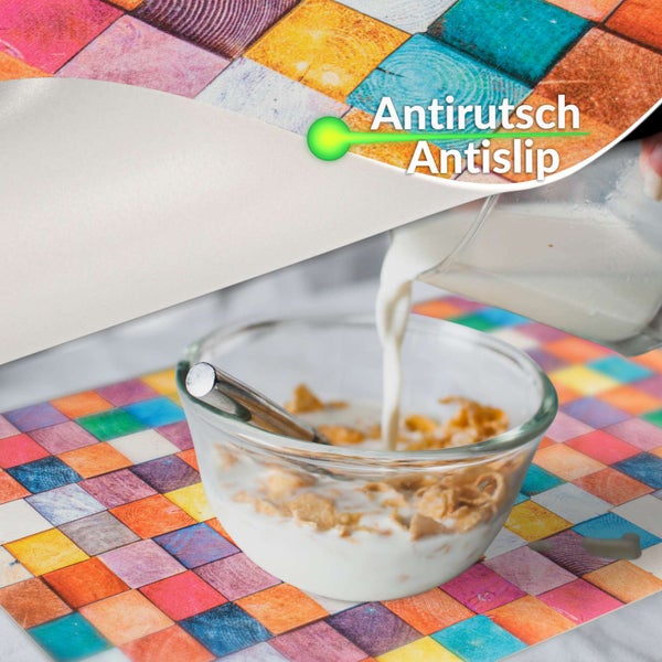 Buntes Tischset mit Karomuster und rutschhemmender Eigenschaft sowie einer Müslischale darauf.
