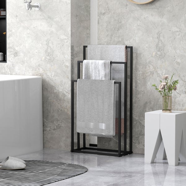 Freistehender Handtuchhalter aus Metall mit drei Ebenen in einem hellen Badezimmer mit Marmoroptik, Badewanne und einem Hocker.