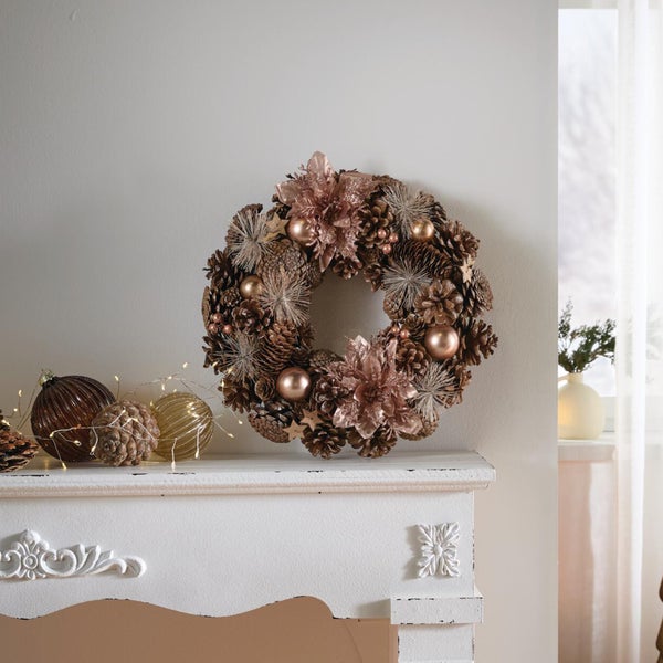 Weihnachtskranz aus Tannenzapfen mit Blumen und Kugeln auf einem Kaminsims dekoriert als festliche Inneneinrichtung.