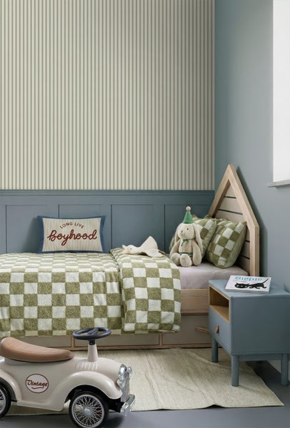 Vliestapete mit feinen vertikalen Streifen in einem hellen Kinderzimmer mit Hausbett und blau-grauer Wandtäfelung.