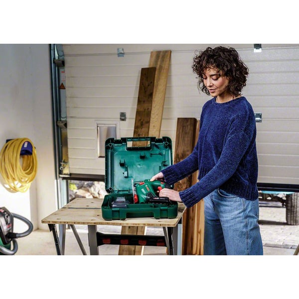 Zwei Bosch Werkzeugkoffer aus Kunststoff auf einem Holztisch, einer geschlossen und einer geöffnet mit Akku-Stichsäge, Akku und Ladegerät.