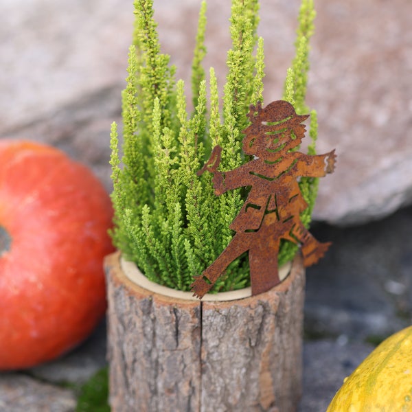 Herbstliche Dekoration mit Erika-Pflanze, Holzpflanzgefäß und Gartenstecker