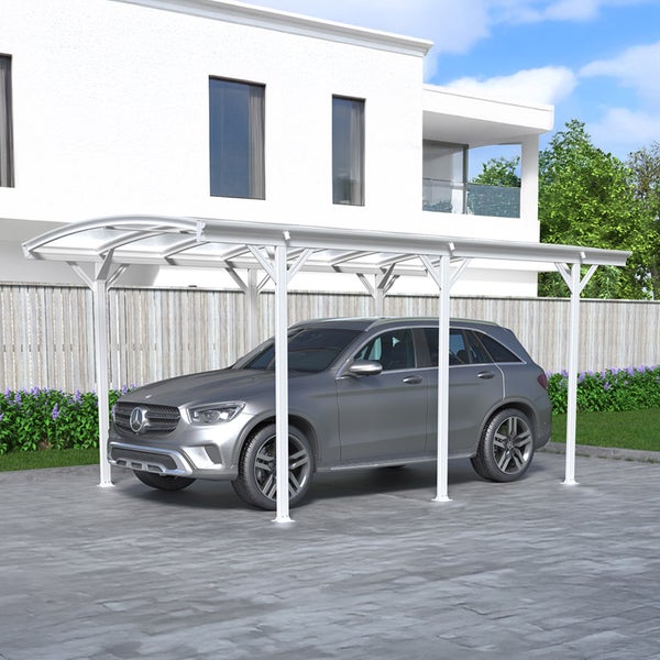 Ein silberfarbener Personenkraftwagen steht unter einem Carport vor einem Haus.