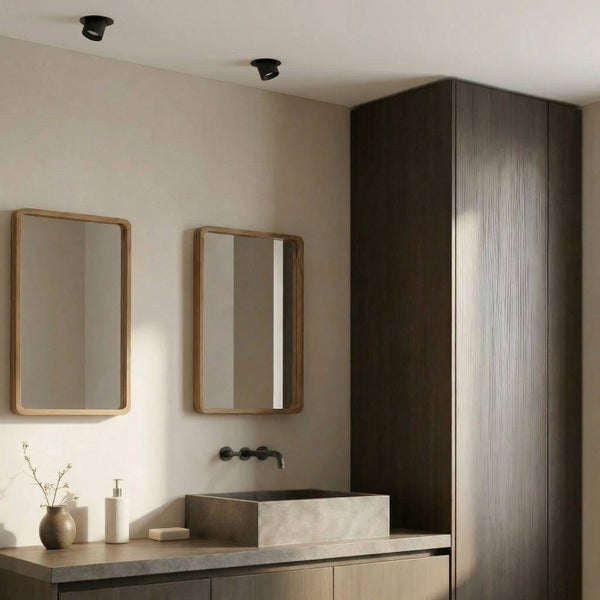 Modernes Badezimmer mit zwei rechteckigen Spiegeln mit Holzrahmen, Steinwaschbecken, Wandarmatur, dunklem Holzschrank und Deckenstrahlern.