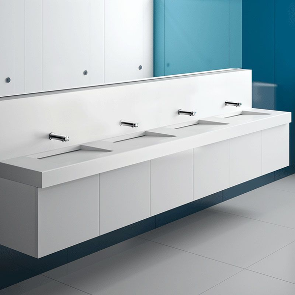 Moderner, wandhängender Reihenwaschtisch in Weiß mit vier integrierten Waschbecken und verchromten Wandarmaturen in einem hellen Badezimmer.