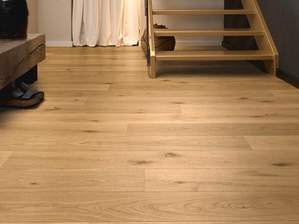 Holzdielenboden in einem Wohnraum mit Treppe und Vorhängen im Hintergrund