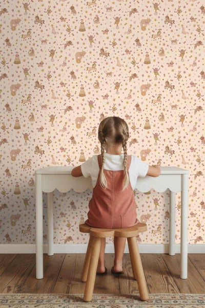 Kindertapete mit Zirkusmotiven in einem Kinderzimmer mit Kind an einem weißen Schreibtisch auf einem Holzstuhl
