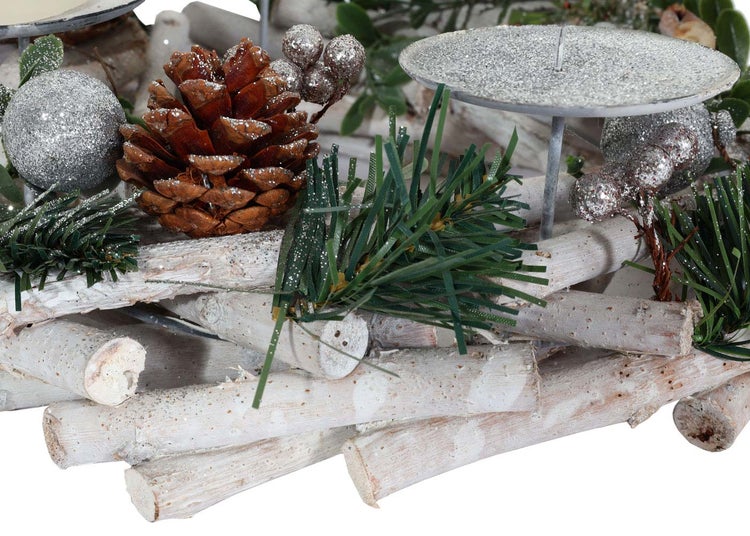 Dekoration mit Tannenzapfen, künstlichen Tannenzweigen, Christbaumkugeln und Kerzenhaltern auf einem Untergrund aus Holzstämmen