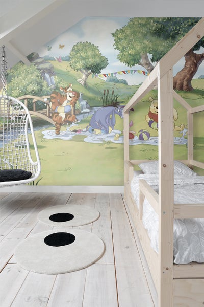 Kinderzimmer mit Winnie Puuh Wandbild, Holzhausbett und runden Teppichen
