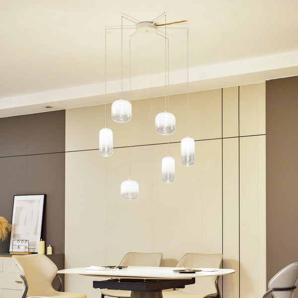 Sechsflammige LED-Pendelleuchte mit zylindrischen Glasschirmen in einem modern eingerichteten, hellen Esszimmer über dem Esstisch.