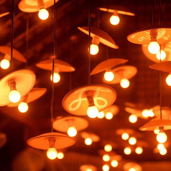 Mehrere hängende Pendelleuchten mit flachen Schirmen in Terrakotta-Optik und warm leuchtenden Glühbirnen, teilweise mit weißen Mustern.