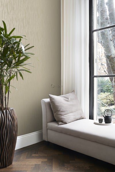 Raumansicht mit Tapete, Liege und Zimmerpflanze in einem strukturierten Übertopf.