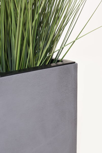 Künstliches Gras in einem grauen rechteckigen Pflanzkübel mit Betonoptik.