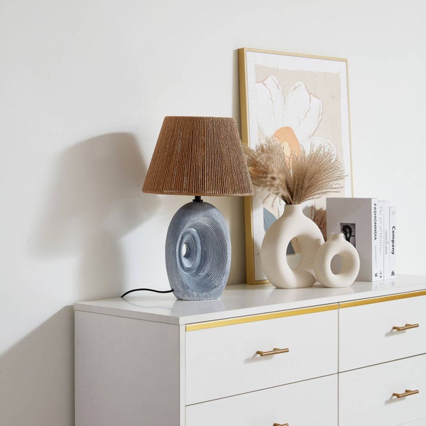 Dekorative Szene mit einer Tischleuchte, Vasen, Büchern und einem gerahmten Bild auf einer Kommode