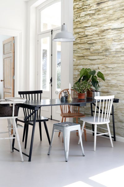 Esszimmer mit Esstisch, Stühlen und Wand in Steinoptik.