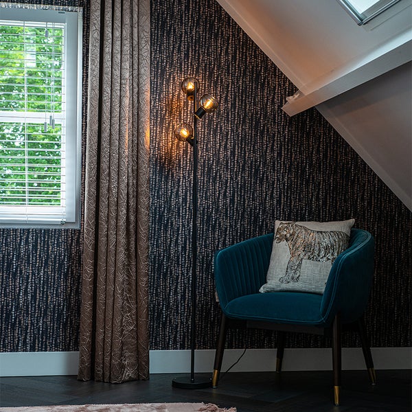 Einrichtungsszene mit Vorhängen, Stehlampe und Sessel mit Kissen