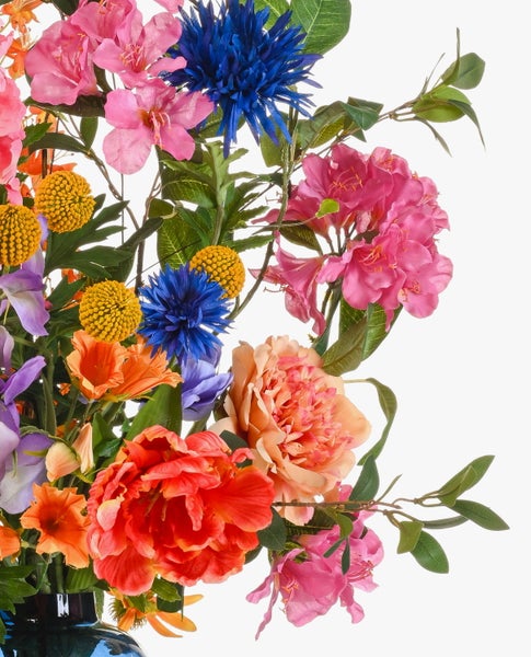 Künstliches Blumenarrangement mit pinkfarbenen Rhododendren, orangefarbenen Steppenkerzen und lila Lilien mit grünen Blättern.