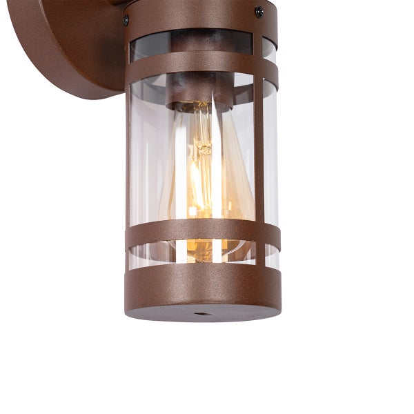 Außenwandleuchte mit zylindrischem Metallkäfig, Klarglas und einem leuchtenden Filament-Leuchtmittel.