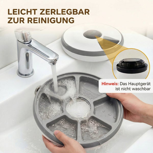 Futternapfeinsatz eines Futterautomaten wird zur Reinigung unter fließendes Wasser in ein Waschbecken gehalten.