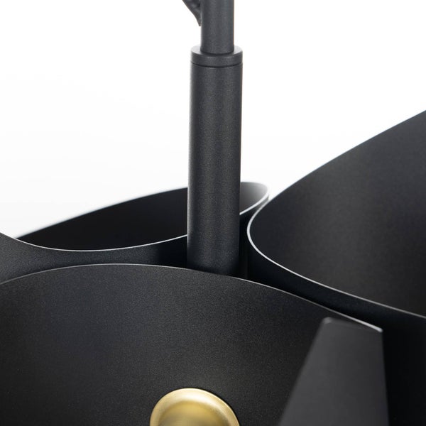 Detailansicht von schwarzen, gebogenen Metallelementen einer Leuchte mit einem goldfarbenen Detail.