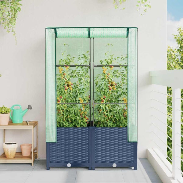 Kompaktes Foliengewächshaus auf einem hellen Balkon mit Tomatenpflanzen und dunklem Sockel in Rattan-Optik.