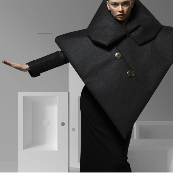 Frau mit geometrischem Mantel vor Badezimmermöbeln