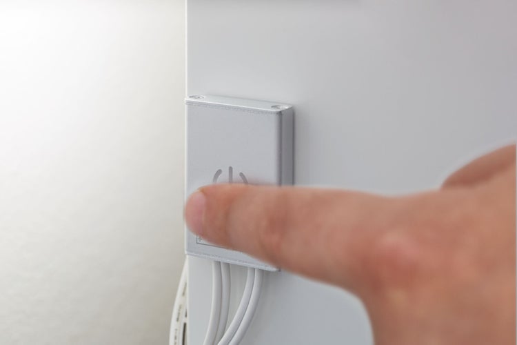 Finger betätigt einen Berührungssensor mit Ein-und-Aus-Symbol an einem Möbelstück.