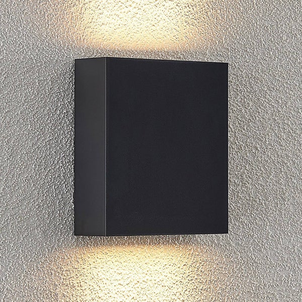 Quadratische Außenwandleuchte in Anthrazit mit Lichtaustritt nach oben und unten an einer strukturierten Wand.