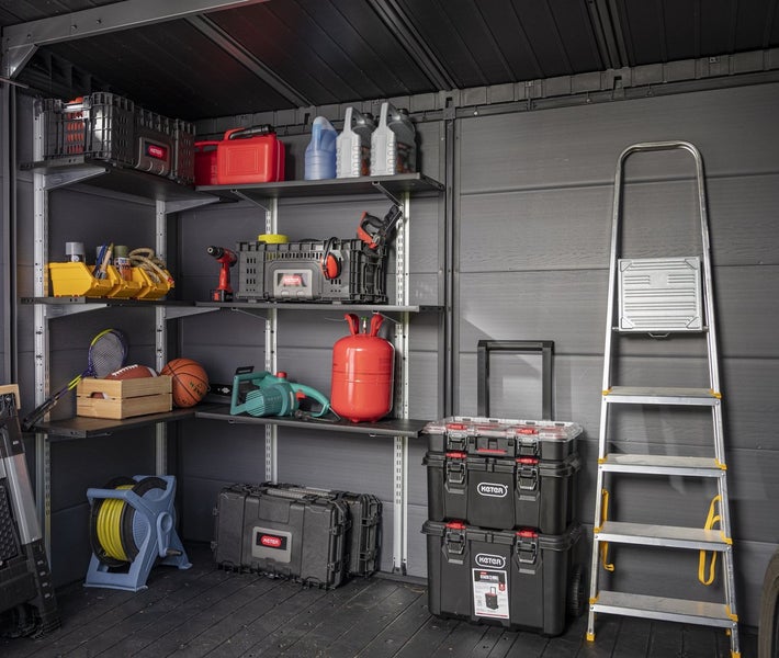 Organisierter, geräumiger Innenraum eines Gartenhauses aus Kunststoff mit Metallregalen, Keter Werkzeugboxen, Schlauchaufroller und einer Stehleiter.