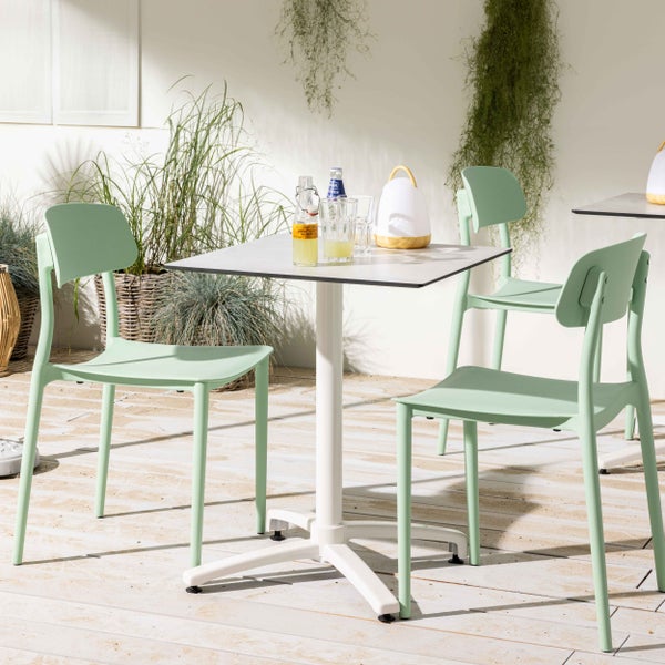 Modernes Gartenmöbel-Set aus einem weißen Bistrotisch und hellgrünen Kunststoffstühlen auf einer hellen Holzterrasse.