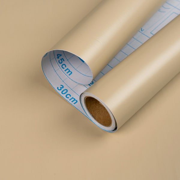 Rolle selbstklebende Folie in Beige mit Rastermaß und Zentimeterangaben auf der Rückseite.