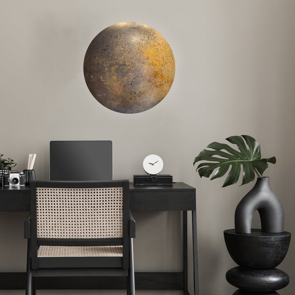 Moderner Arbeitsplatz mit schwarzem Schreibtisch, Stuhl mit Wiener Geflecht und großer runder Wanddekoration in Gold und Grau.
