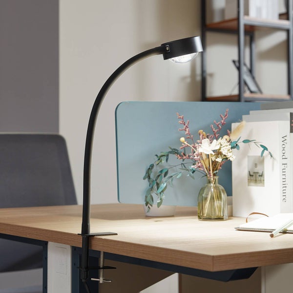 Schreibtisch mit Klemmlampe und Dekorationen für eine gemütliche Arbeitsatmosphäre.