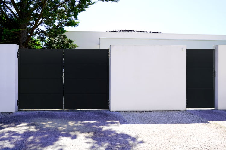 Schwarzes Gartentor mit weißen Mauerelementen.