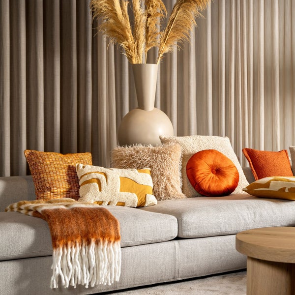 Dekoratives Wohnzimmer mit Sofa, Kissen, Decke und Blumenvase für ein gemütliches Ambiente