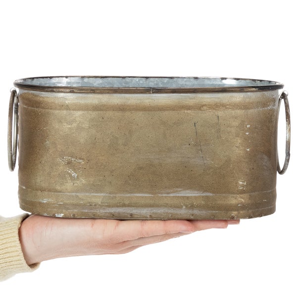 Ovaler Pflanztopf aus Metall mit zwei seitlichen Griffringen, auf einer Hand präsentiert zur Veranschaulichung der Größe.