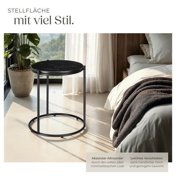 Moderner runder Beistelltisch mit schwarzer Platte in Marmoroptik und Metallgestell in einem hellen minimalistischen Schlafzimmer.