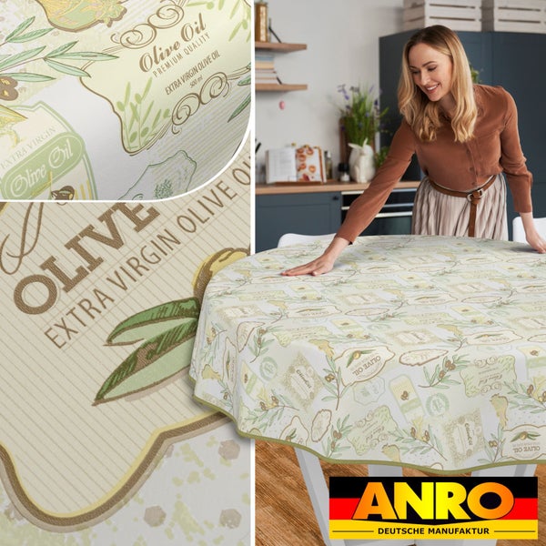 Frau legt Wachstuch Tischdecke mit Olivenöl Motiv auf Tisch in Küche