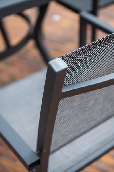 Nahaufnahme der Rückenlehne eines Gartenstuhls aus anthrazitfarbenem Metall mit Netzgewebe.