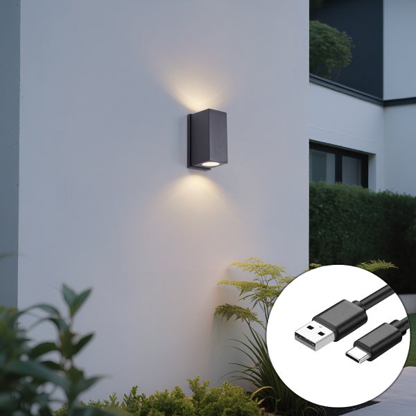 Wiederaufladbare LED Außenwandleuchte in Anthrazit mit Lichtaustritt nach oben und unten an einer Hauswand, inklusive USB C Ladekabel.