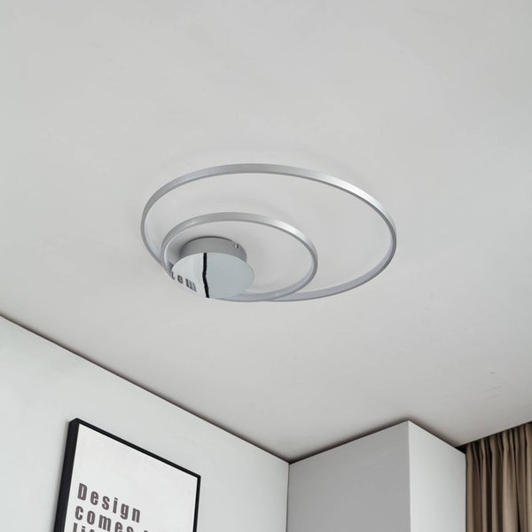 Moderne Deckenleuchte mit drei metallenen Ringen auf einer runden Basis in einem hellen Raum mit einem Poster und Vorhängen.