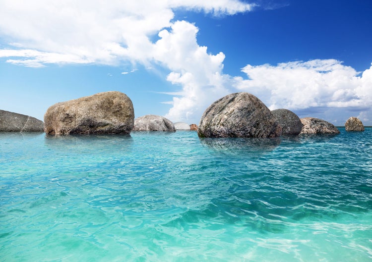 Szene mit Felsen im Wasser unter blauem Himmel und Wolken