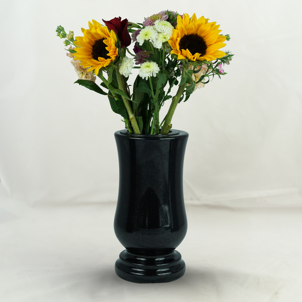 Schwarze Grabvase aus Stein mit einem bunten Blumenstrauß bestehend aus Sonnenblumen und Chrysanthemen.