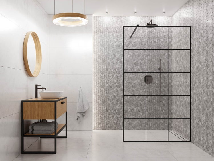 Helles Badezimmer mit Holz-Waschtisch, rundem Spiegel, Walk-In Dusche mit schwarzer Gitter-Glaswand und grauen Mosaikfliesen im Fischgrät-Muster.