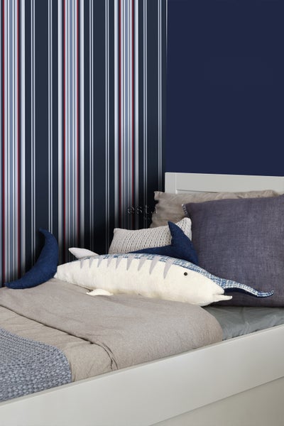 Kinderzimmer mit gestreifter Tapete und dekorativem Fischkissen auf dem Bett