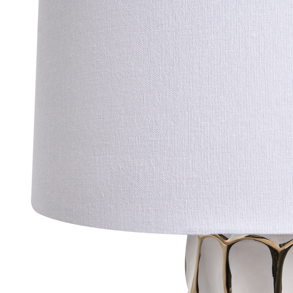 Detailaufnahme eines weißen Textillampenschirms mit goldfarbenem Standfuß.