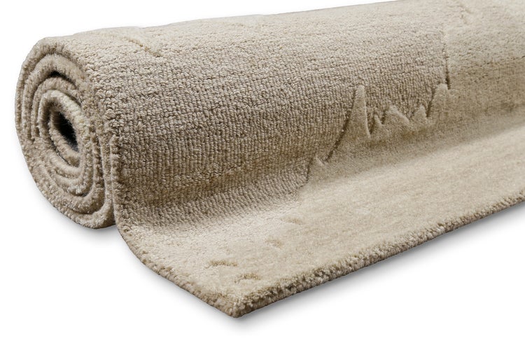 Aufgerollter beiger Teppich mit strukturierter Oberfläche und Muster.